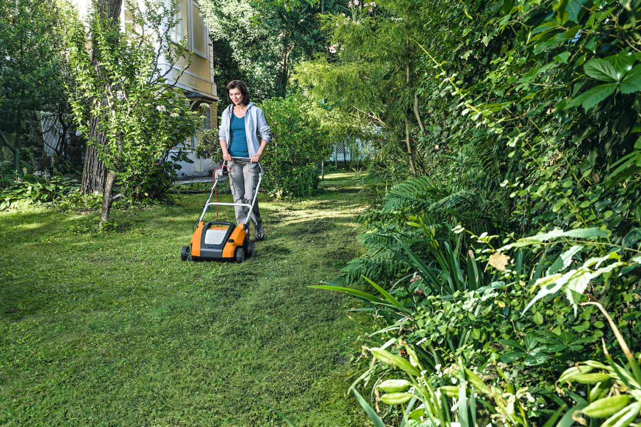 Frau vertikutiert Rasen mit dem STIHL Elektro-Rasenlüfter RLE 240