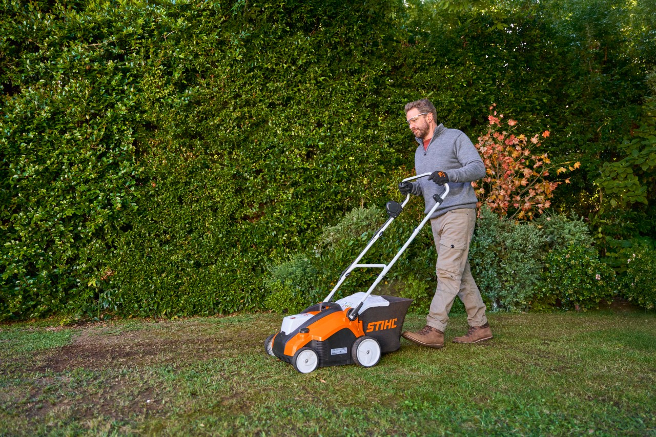 Ein Mann vertikutiert den Rasen mit dem STIHL RLA 240