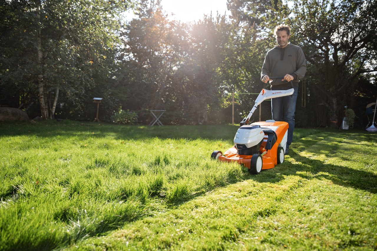 Mann mäht den Rasen auf seinem Grundstück mit einem STIHL Akku-Rasenmäher RMA 448 VC
