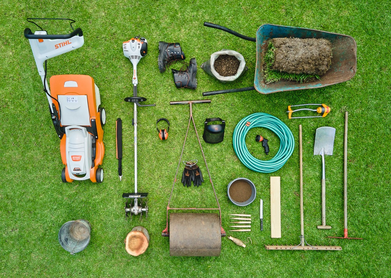 Vogelperspektive auf den Akku-Rasenmäher STIHL RMA 339 C und auf weiteres benötigtes Werkzeug, um Rollrasen zu verlegen 