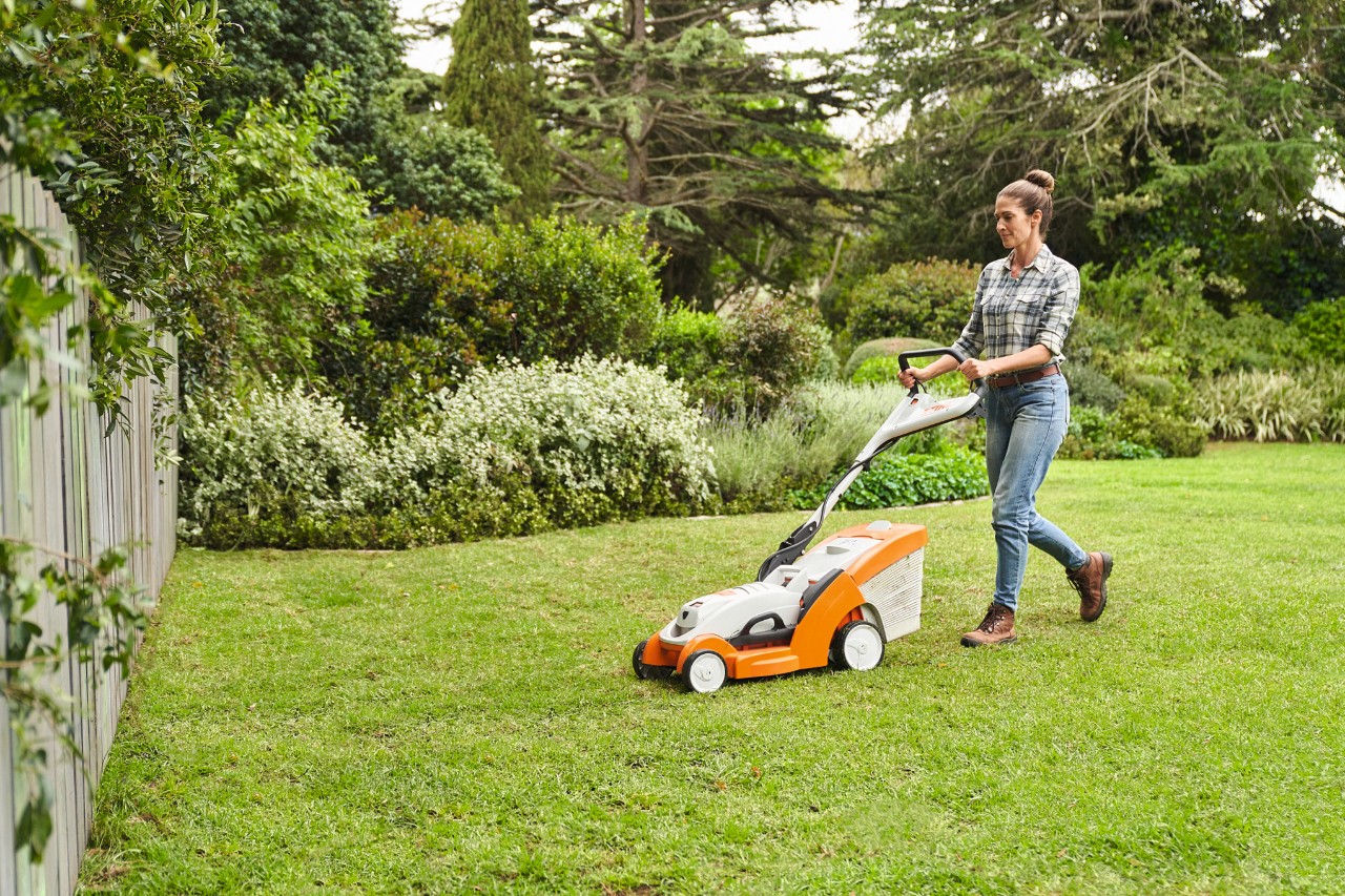 Frau mäht selbst verlegten Rollrasen mit einem Akku-Rasenmäher STIHL RMA 339 C