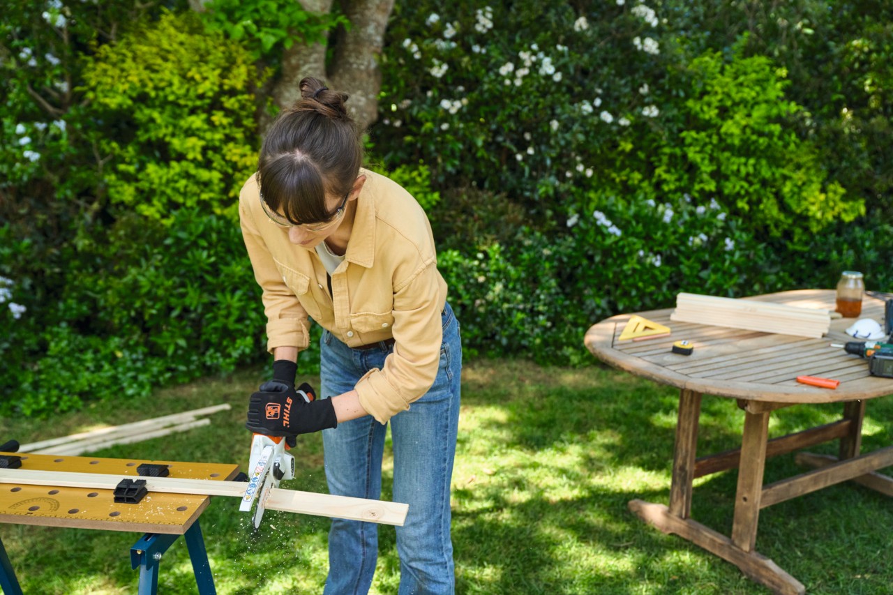 Eine Frau sägt eine Latte mit dem Gehölzschneider STIHL GTA 26 zu