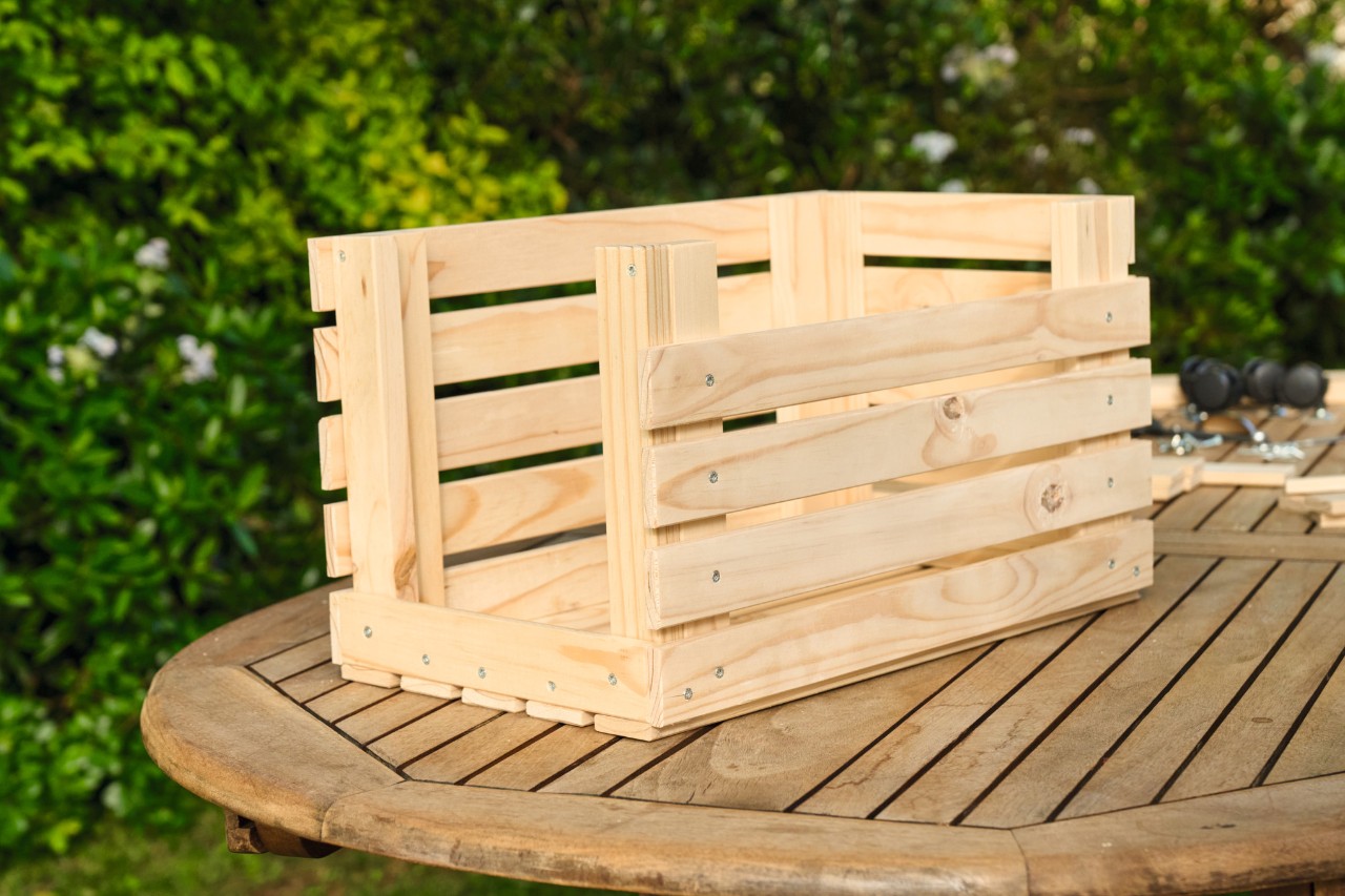 Die Holzlatten werden an allen Seiten des hölzernen Blumenkastens befestigt