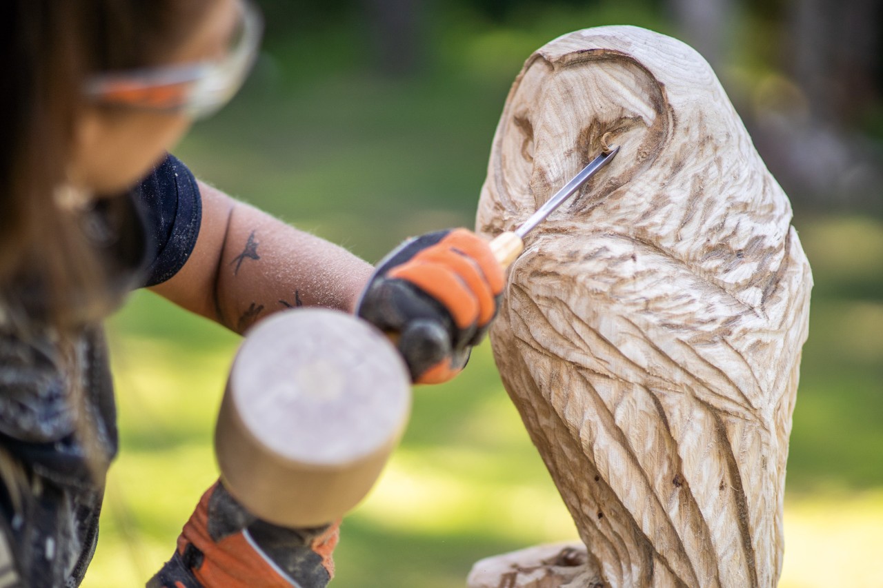 Mit einem Stemmeisen werden Feinheiten an der Eule aus Holz herausgearbeitet
