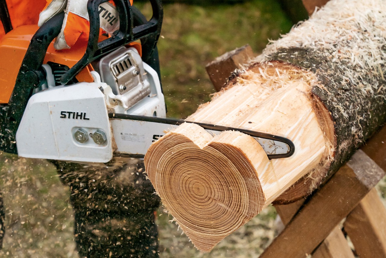 Mit der STIHL Benzin-Kettensäge MS 170 werden Scheiben vom herzförmigen Rundholzes abgesägt