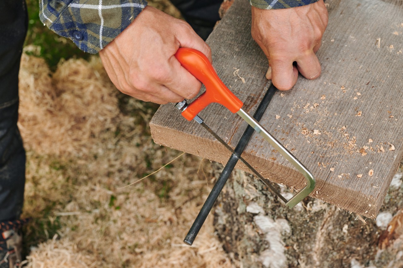 Metallstab wird für Holzstern am Stab mit Eisensäge auf gewünschte Länge gesägt