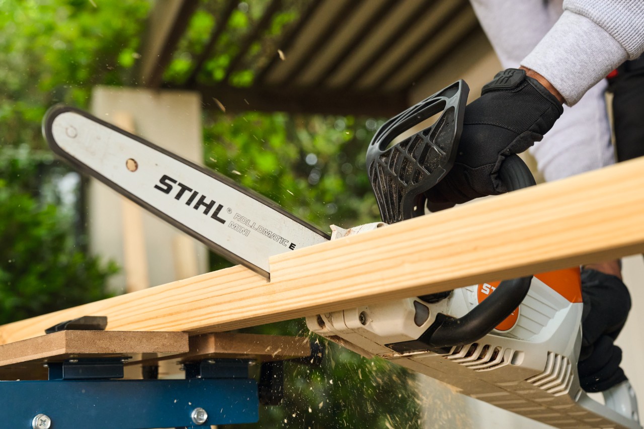 Ein Mann sägt eine Seitenstrebe für ein Fußballtor mit einer STIHL MSA 70 zurecht