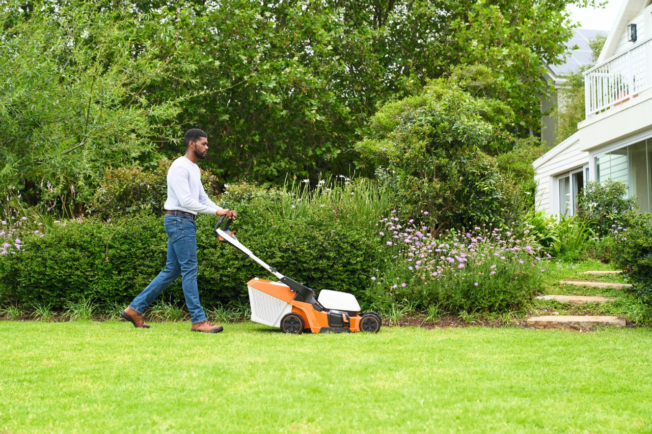 Ein Mann mäht den Rasen mit einem Rasenmäher STIHL RMA 448 V