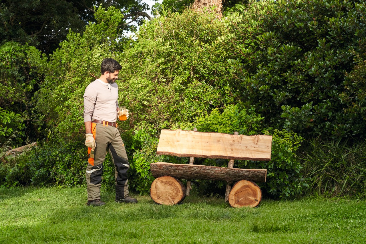 Ein Mann betrachtet zufrieden die fertige, selbstgebaute Gartenbank