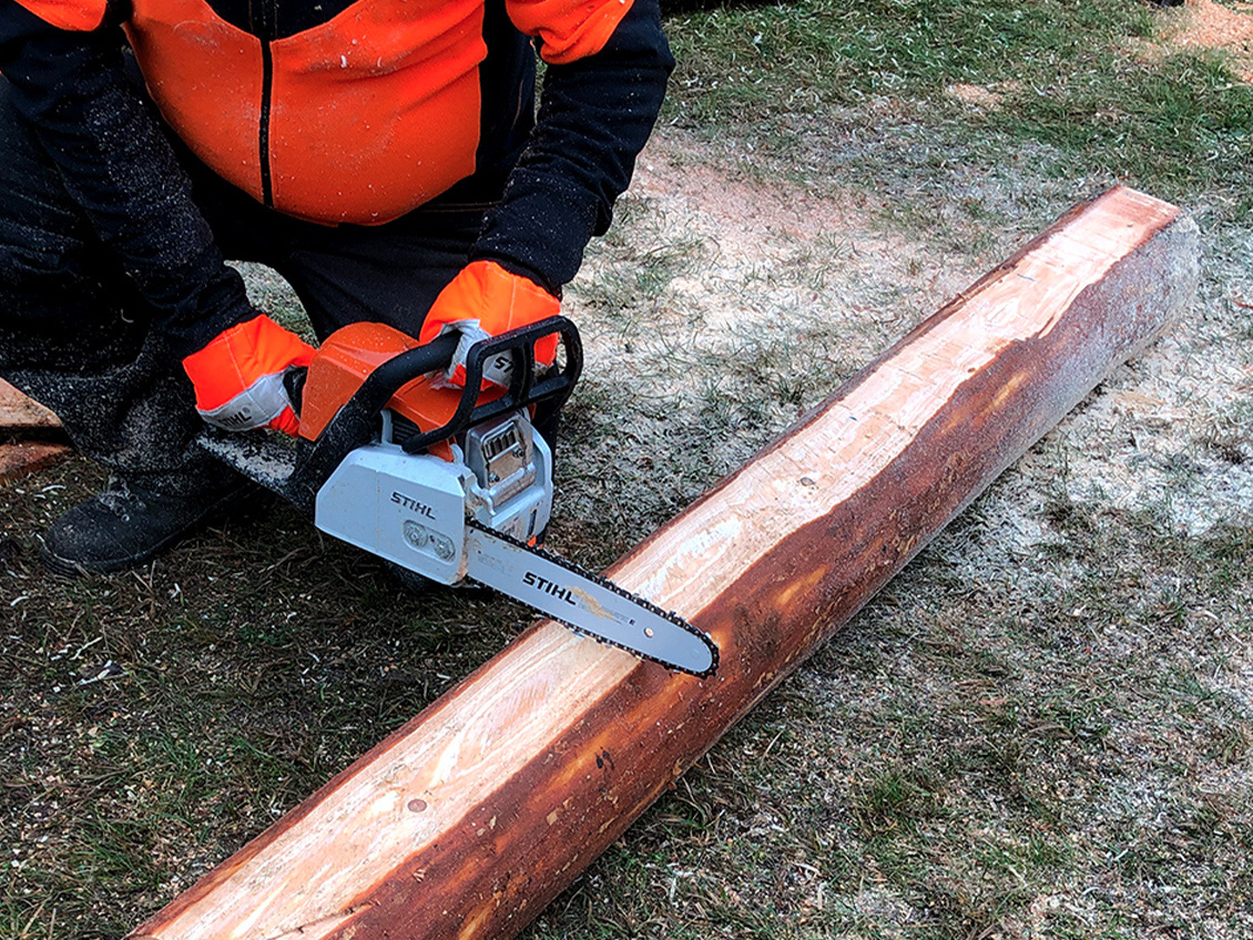  Person in Schutzkleidung längt das Stammstück mit einer STIHL Kettensäge ab