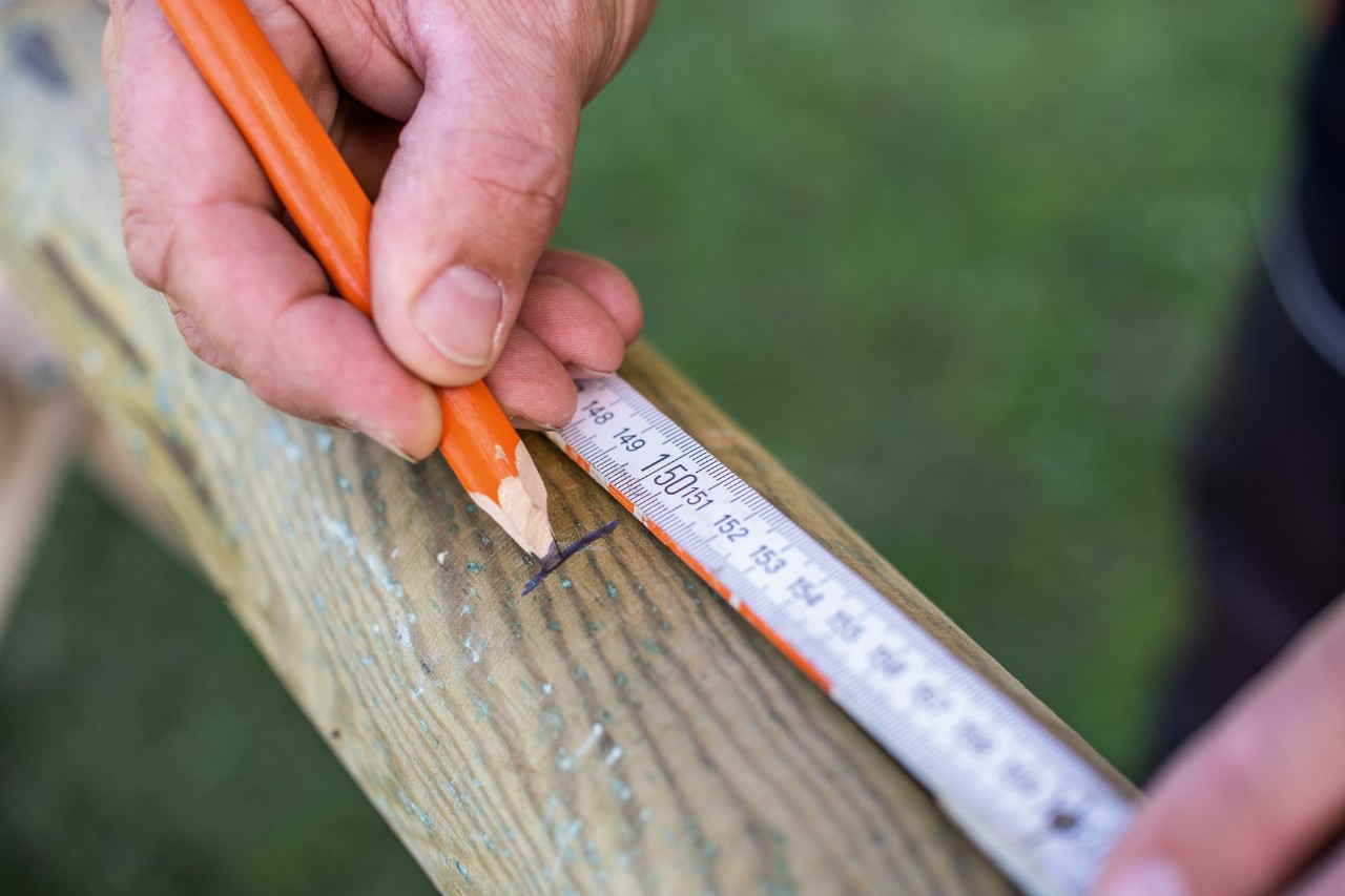 Mit Bleistift und Zollstock wird die Länge auf den Palisaden eingezeichnet