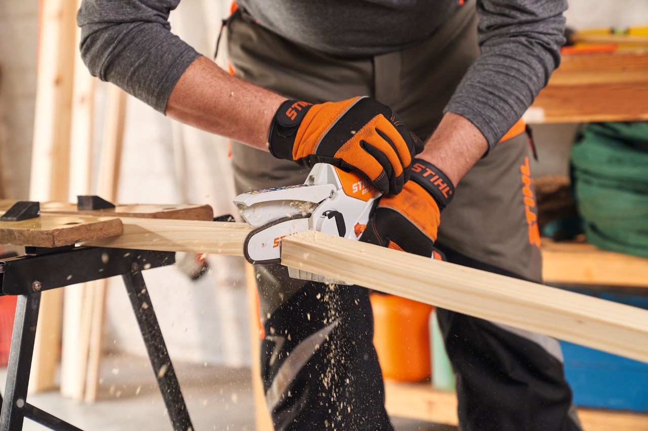 Person mit Schutzhandschuhen STIHL Function Protect längt Rahmenleisten für Sichtschutz mit Gehölzschneider STIHL GTA 26 ab