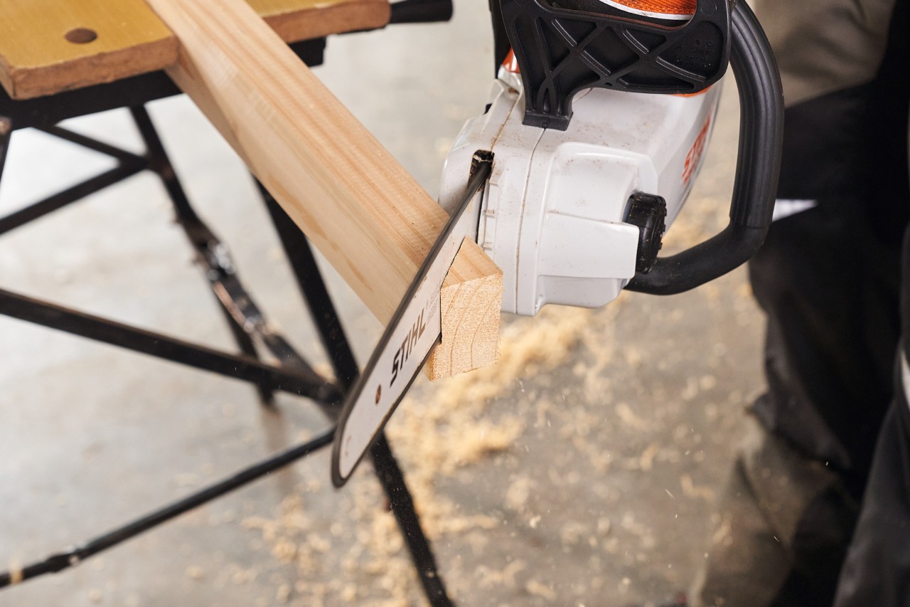 Mit einer Akku-Motorsäge STIHL MSA 140 werden die Kanthölzer für die Füße eines Sichtschutzzaunes abgelängt    