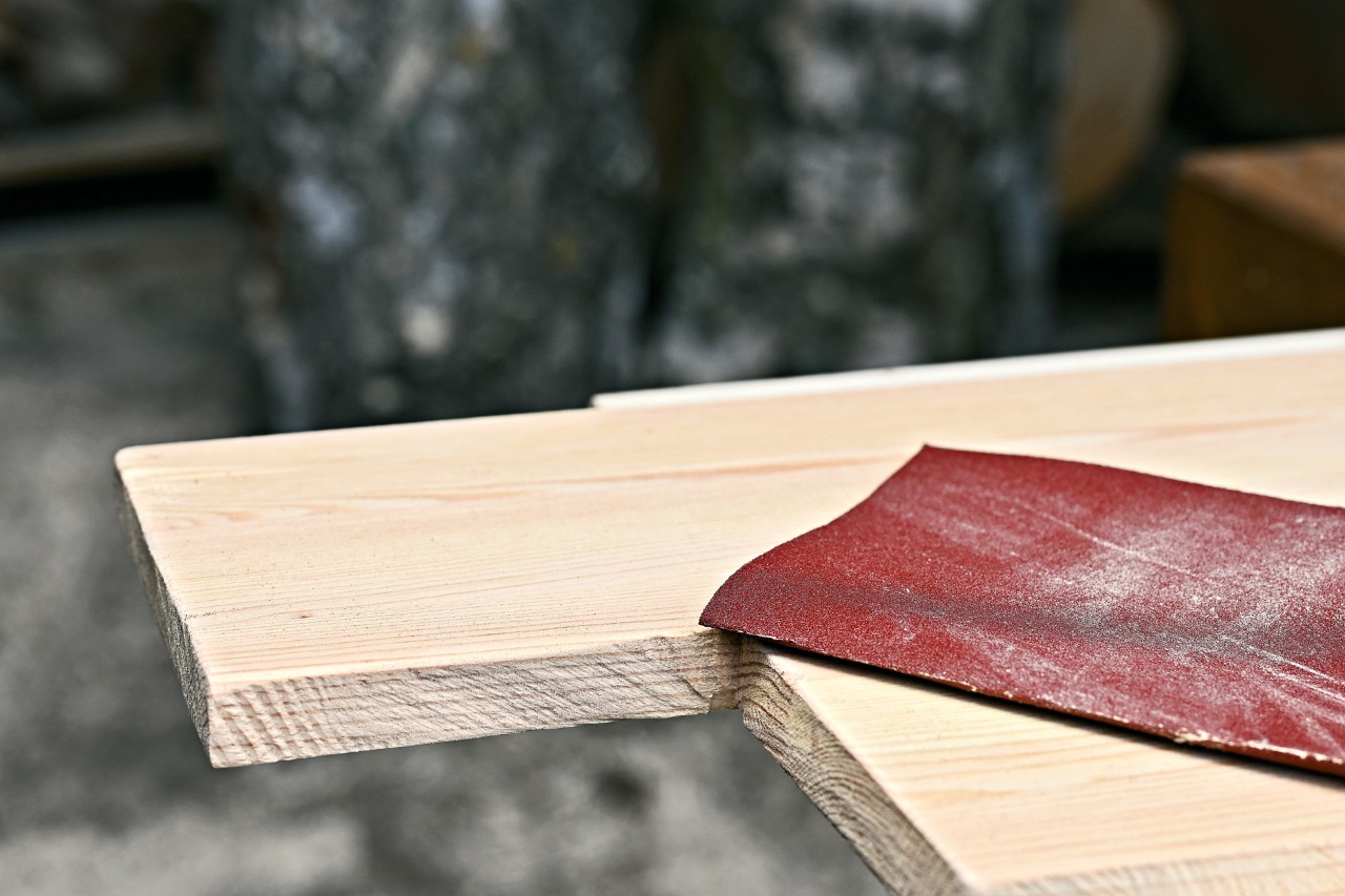 Schleifpapier auf einem Holzbrett, aus dem der Eingang für ein Igelhaus gesägt wurde