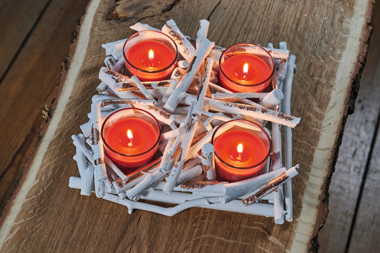 Selbstgemachter Adventskranz aus Ästen mit roten, brennenden Teelichtern 