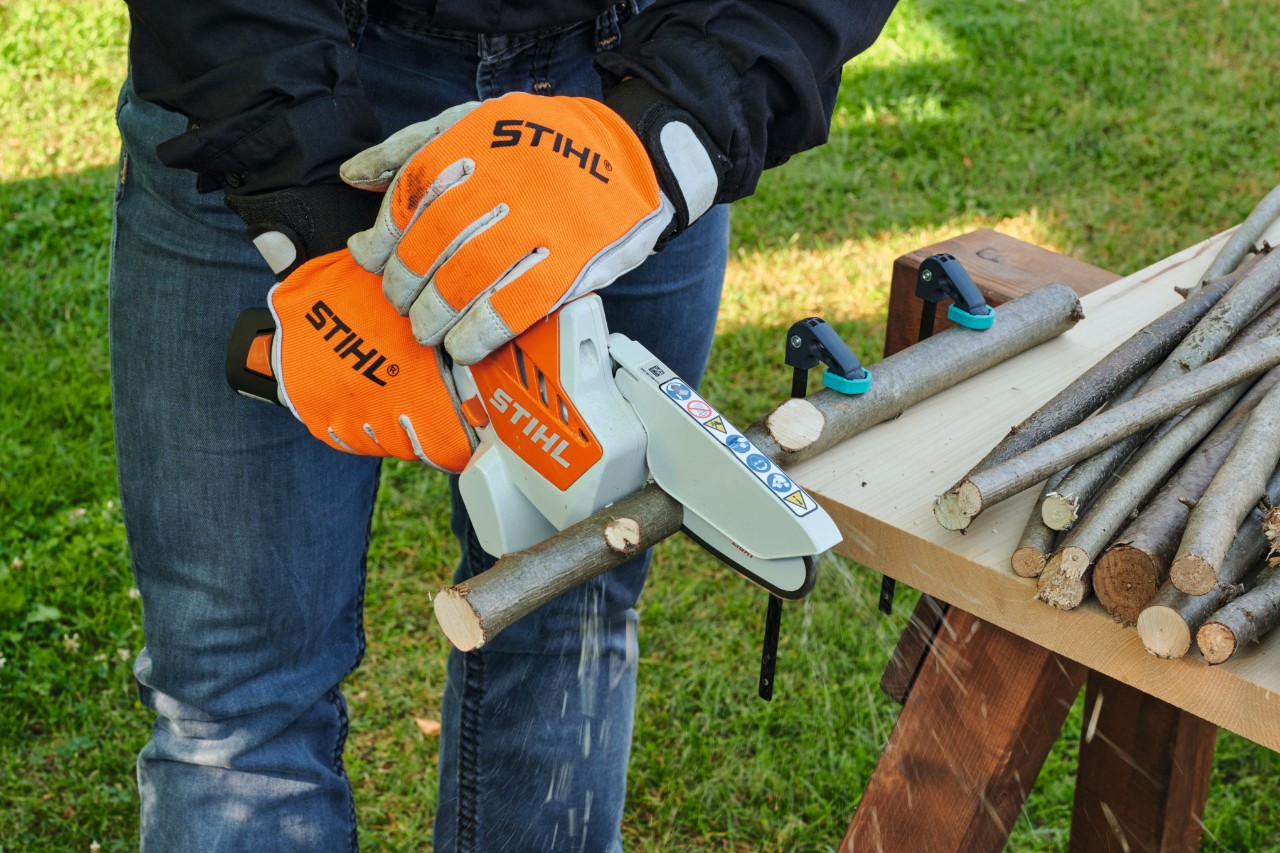 Person mit Schutzhandschuhen schneidet Äste für einen Adventskranz mit einem STIHL Akku-Gehölzschneider GTA 26