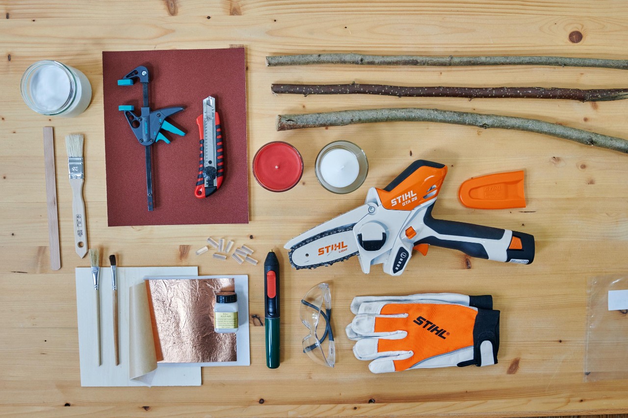 Werkzeug und Material für einen Adventskranz aus Ästen liegen sortiert auf einer Holzplatte