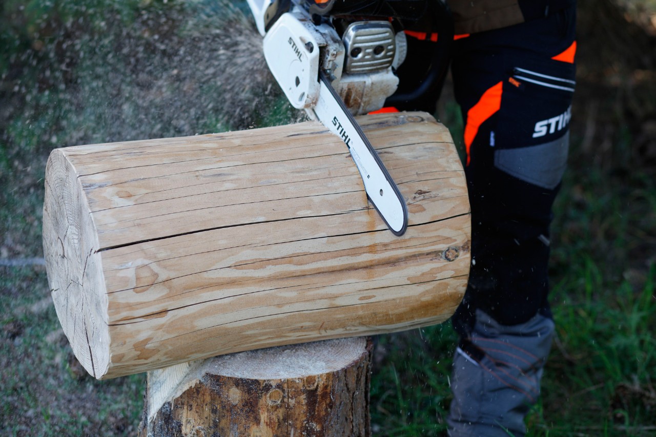 Mit einer STIHL Benzin-Motorsäge MS 231 C wird ein Baumstamm auf die gewünschte Länge für einen Hocker gekürzt