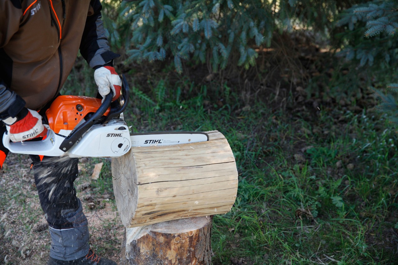Mit einer STIHL Benzin-Motorsäge MS 231 C wird ein Baummstamm in zwei Hälften geteilt, um einen Hocker selber zu machen