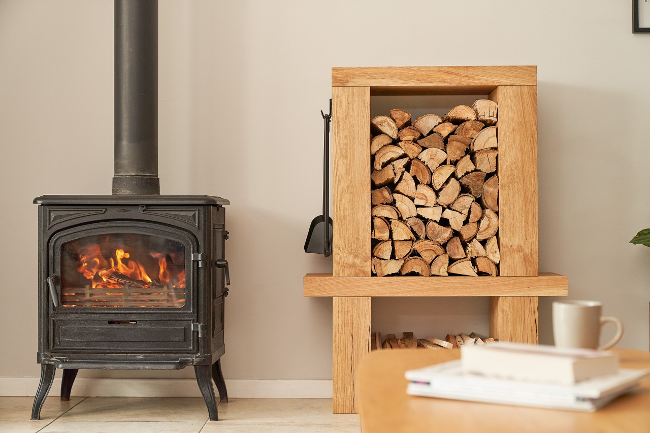 Kamin und mit Holzscheiten befülltes Kaminholzregal zum Selberbauen in einem Innenraum 