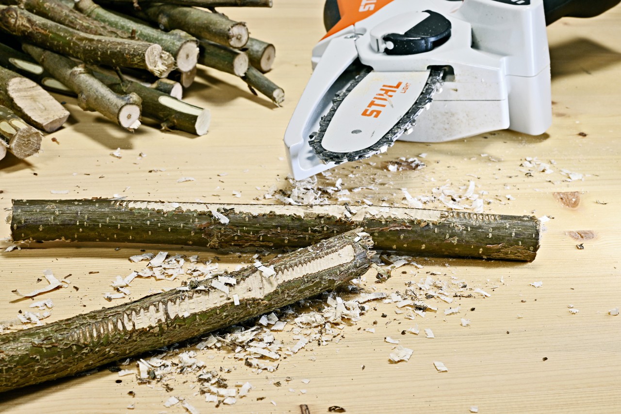 Äste mit aufgerauter Oberfläche, dahinter ein STIHL Akku-Gehölzschneider GTA 26