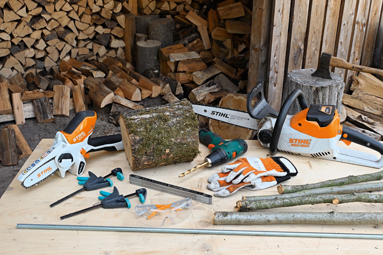 Material und Werkzeug, um einen Weihnachtsbaum aus Holz selber zu bauen, darunter die Akku-Motorsäge STIHL MSA 120 und der Akku-Gehölzschneider STIHL GTA 26 