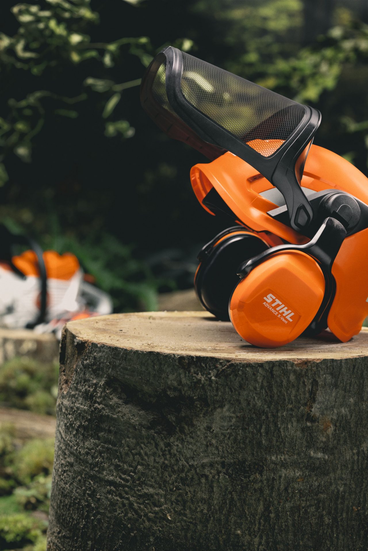 Nahaufnahme des STIHL Helmsets Advance X-Vent ProCom auf einem Baumstamm