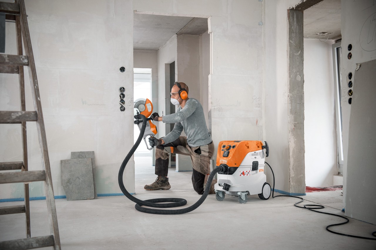 Mann nutzt STIHL Nass- und Trockensauger SE 133 ME bei der Arbeit mit einem STIHL Trennschleifer TSA 230