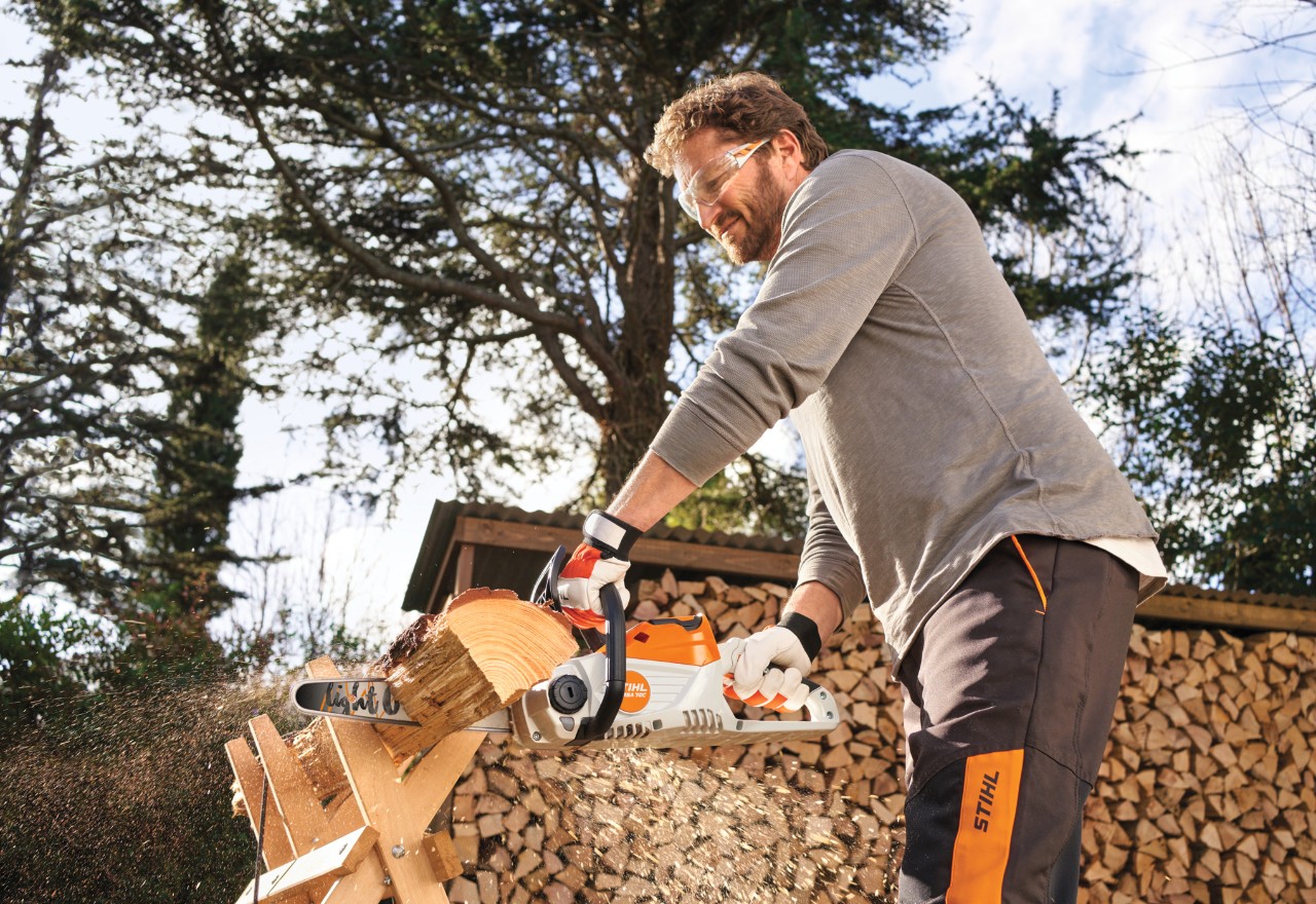 Mann nutzt STIHL MSA 70 zum Holzschneiden im Garten
