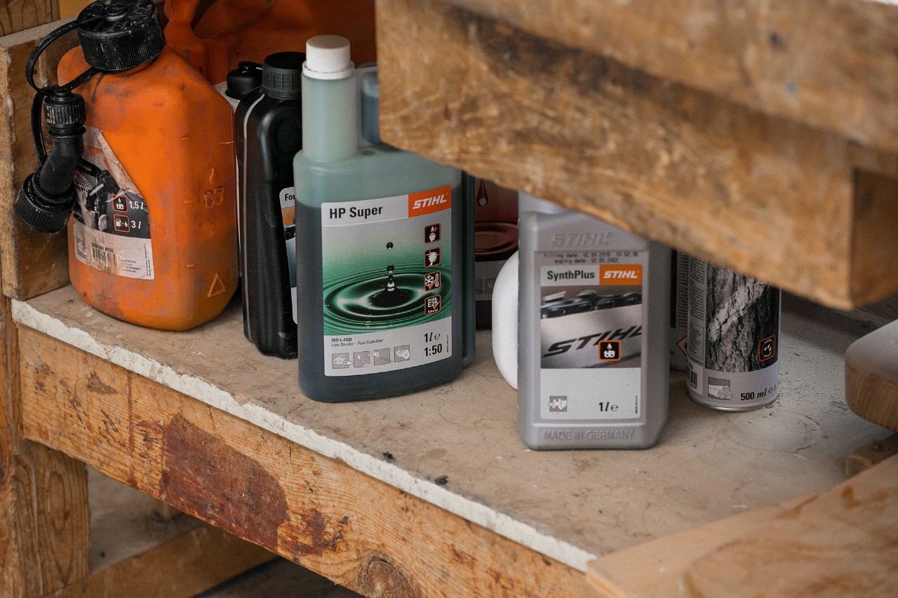 STIHL Sägekettenhaftöl SynthPlus und STIHL Zeitaktmotorenöl HP Super neben anderen Betriebsstoffen in einem Regal