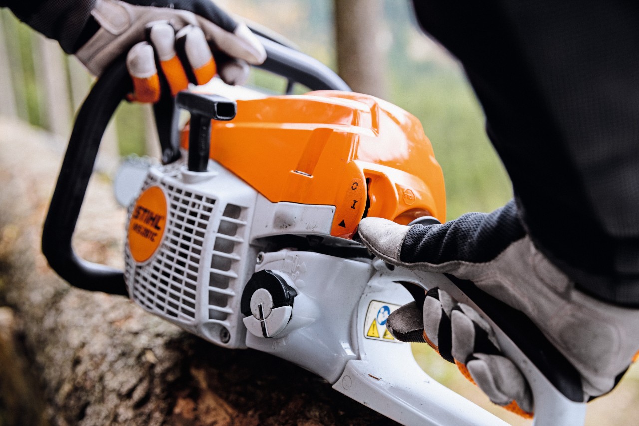 Nahaufnahme einer STIHL Benzin-Kettensäge MS 261 C-M, die von Person mit Schutzhandschuhen gestartet wird