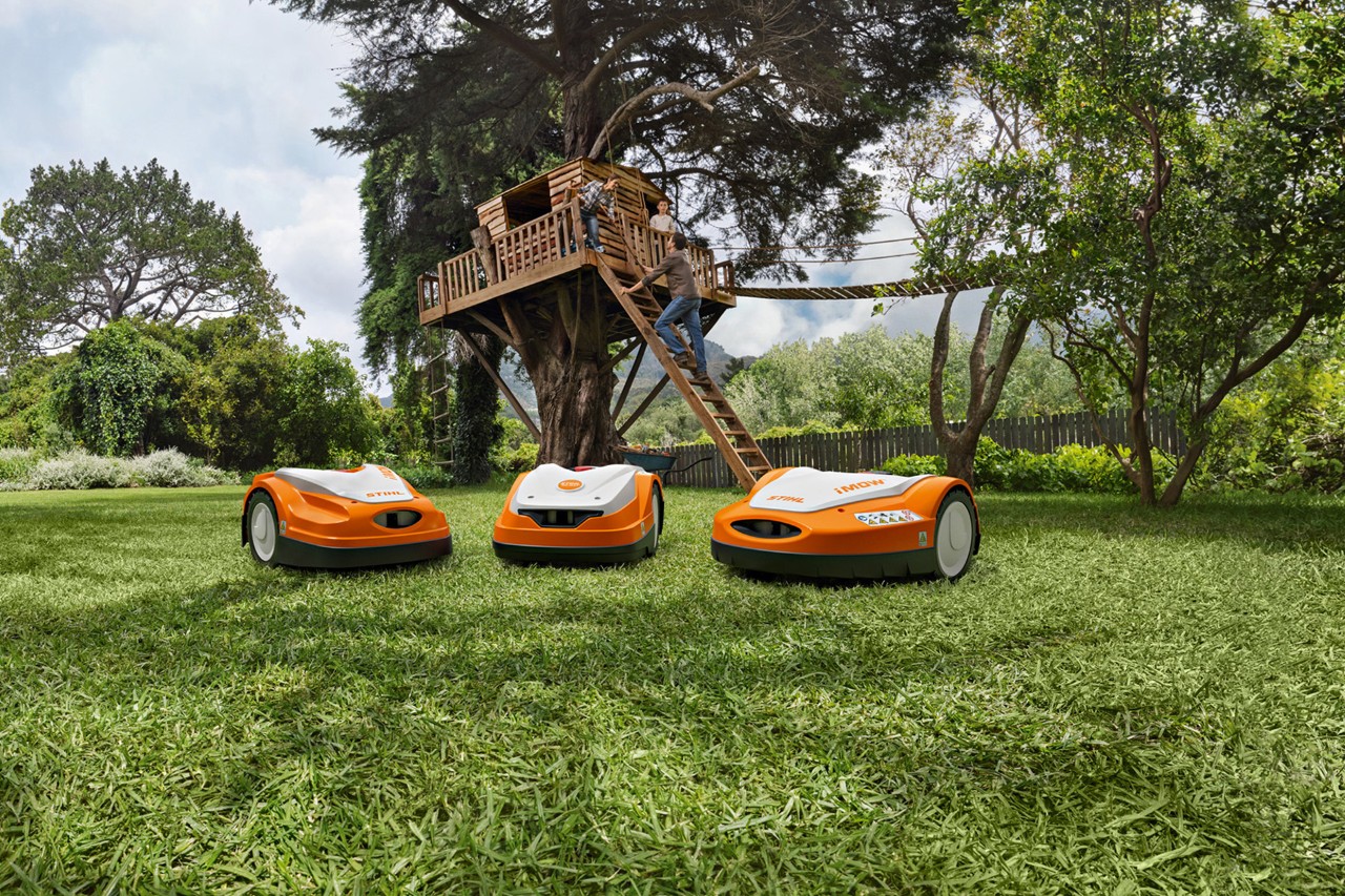 Die verschiedenen STIHL iMOW® Mähroboter auf grünem Rasen im Garten