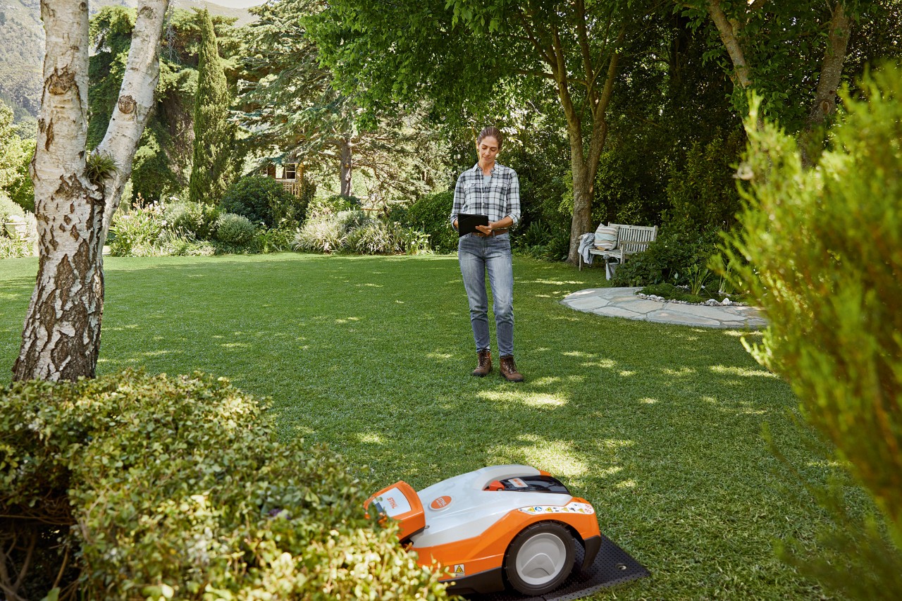 Frau bedient den STIHL iMOW® Mähroboter 522 über ein Tablet