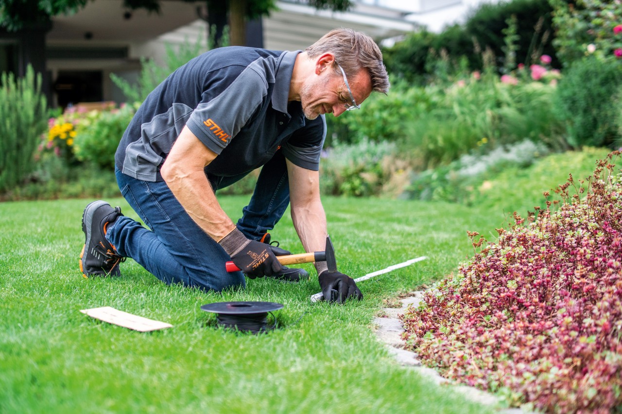 Ein STIHL Fachhändler beim Verlegen des Begrenzungsdrahtes